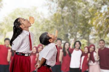 kids against each other eating indonesian cracker on independence day