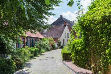 Fototapeta na wymiar Straße im Rundwarfendorf Rysum in Ostfriesland, Krummhörn, Niedersachsen, Deutschland