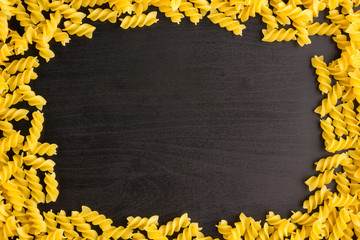 Frame of A pile of pasta spiral fusilli on black background with copyspace