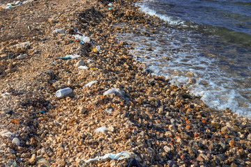 Lots of garbage by the sea. Plastic bottles and other garbage up on beach. Plastic pollution environmental problem.