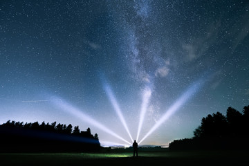 Mann leuchtet mit Taschenlampe die Milchstraße in der Nacht an