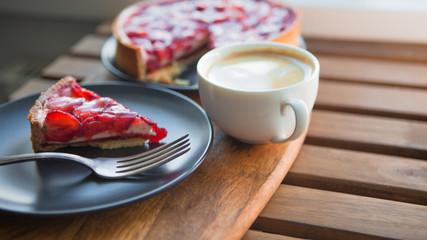 Still life with a Cup of coffee and sweet dessert with strawberries, cheesecake cake with slices of berries in jelly on top.