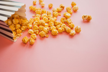 Fototapeta premium Popcorn in paper bag scattered on pink background top view