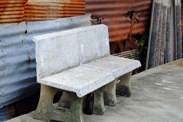 An empty old stone bench on rough ground cement with rusty zinc wall background 