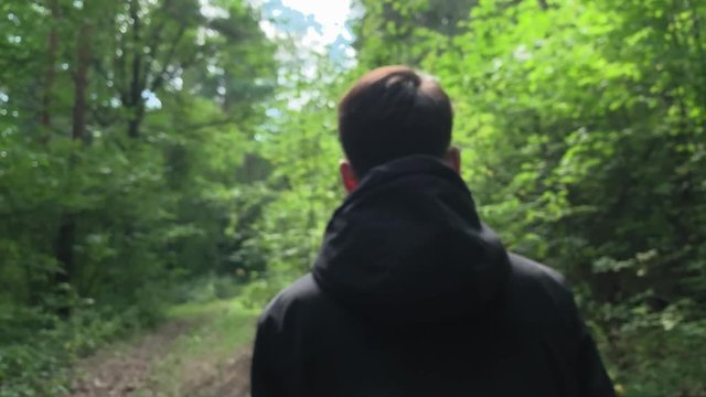 Slow motion . Man in a black jacket walking  in the woods on a sunny day. Footages UHD 4K 60FPS