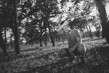 Tired sportsman wipe sweat and relax after training in the forest