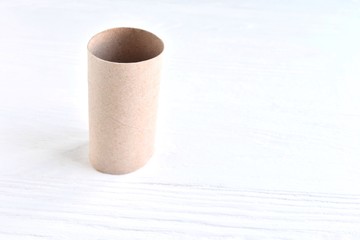 Cardboard sleeve from a roll of toilet paper with selective focus on neutral background. Out of toilet paper.  Recycled cardboard cylinder from toilet paper on white backdrop with empty space for text