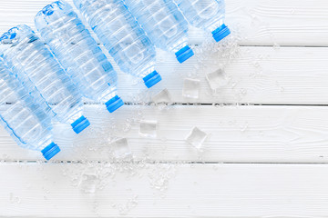 empty plastic bottles for pure water with ice cubes on white wooden background top view mock up