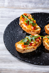 Bruschettas on black stone plate on wooden background