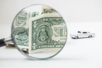 One dollar bills trough magnifying glass. Save money to buy a car. Car insurance.  Business concept