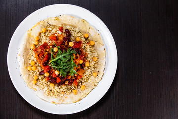 Groats with sauce and vegetables on tortilla