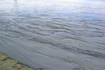 Dirt is the result of wet sand. Abstract gray natural background. Day view of the surface with sky reflections close-up.