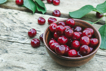 Sweet organic berries in a bowl on old wooden boards.