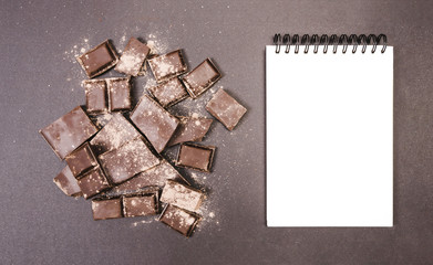 Top view chocolate covered in cocoa with notebook