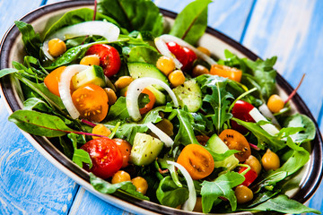 Greek salad with chickpea on wooden background