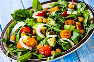 Greek salad with chickpea on wooden background