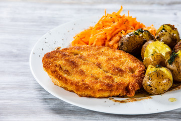 Fried pork chop, boiled potatoes and vegetable salad