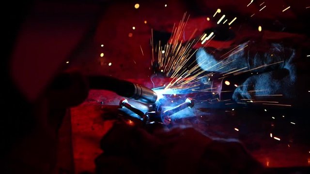 A slow mo close up shot of apprentice learning the ropes on a construction site, futuristic industrial practice sparks flying around quick fix on this job career