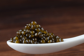 Black sturgeon caviar in ceramic spoon. macro