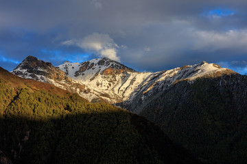 Snow mountains, epic snow covered mountain range - Daocheng Yading Nature Reserve. Ganzi, Garze, Kham Tibetan area of Sichuan Province China. Dramatic lighting during sunset, Clouds and Sky