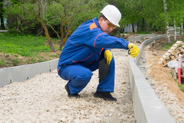 construction worker checks the progress of laying curbstone and rubble mound