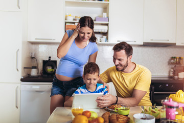 Pregnant woman and her family breakfasting in the kitchen
