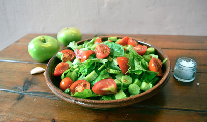 composed salad with lettuce fresh spinach wild cucumber and tomatoes on a wooden table with green apples and thyme