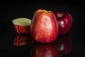 Group of two whole one half of fresh apple red delicious isolated on black glass