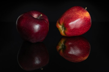 Fototapeta na wymiar Group of two whole fresh apple red delicious one dark and one light isolated on black glass