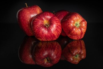 Group of four whole fresh apple red delicious isolated on black glass
