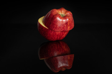 Group of two halves of fresh apple red delicious one on top of the other isolated on black glass