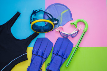 Flippers, mask, trbka, bathing suit, goggles and a rubber cap for scuba diving on a multi-colored background