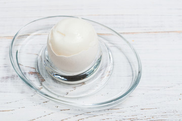 Boiled soft-boiled chicken egg on a white wooden background.