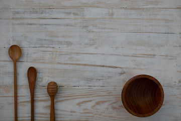 Eco-friendly wooden bowl, spoons and honey stick on wooden table background. Environmentally friendly kitchen utensil flat lay with copy space.