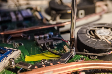 Technical support worker unspins the cover of the computer monoblock with a screwdriver