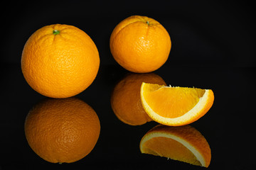 Group of two whole one slice of fresh sweet orange isolated on black glass