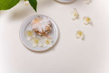 Obraz na płótnie Canvas cake with jam and powdered sugar on the plate with spring jasmine flowers on the white background