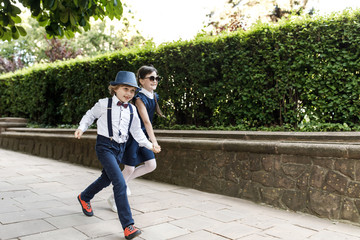 Cute blond guy and cute girl, school year fun time outdoors. Children dressed in school uniform play games in the park