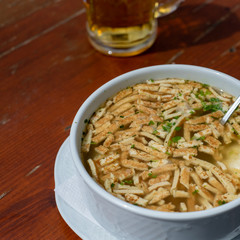Bavarian pancake soup and a glass of beer, top view, cropped, on wooden table, bar setting