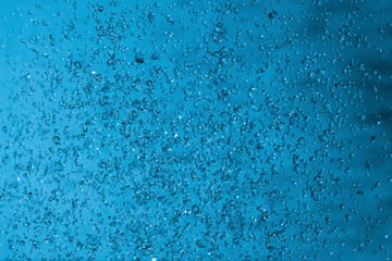 Fototapeta na wymiar Water splashes on blue background. Spray. Drops of water on the glass window. Rain, shower. sprinkle a little, pour