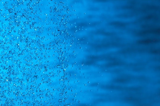 Water splashes on blue background. Spray. Drops of water on the glass window. Rain, shower. sprinkle a little, pour