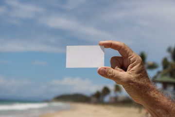 hombre sosteniendo una tarjeta de presentacion en la playa 