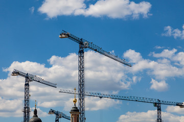 Construction cranes on a cloudy sky background