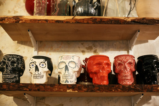 Colorful skulls in city street, halloween street decor. Ceramic painted skulls for Day of Dead on shelf, mexican tradition, Dia de los Muertos. Space for text. Happy halloween