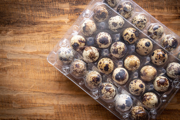 Quail eggs in  packaging on wooden background