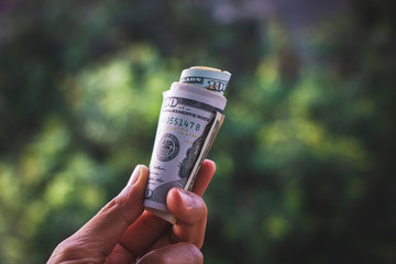 Financial concept, earning concept or donation concept. A roll of US dollar banknotes in hand.