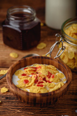 Breakfast with corn flakes, milk and berry syrup