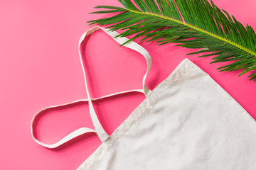 Blank white mockup linen cotton cloth tote bag green palm leaf on fuchsia pink background trendy flat lay. Zero waste reusable eco friendly materials plastic free concept
