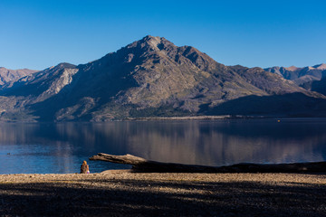 Rear view of a woman sit down next to the lake meditating at Epuyen lake, Puerto Patriada, Patagonia, Argentina