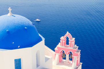 Fototapeta na wymiar Oia Village, Santorini Cyclade islands, Greece. Beautiful view of a blue dome church and a pink towerbell.